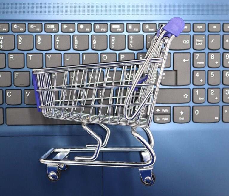 A miniature shopping cart placed on a laptop keyboard symbolizing online shopping and e-commerce.