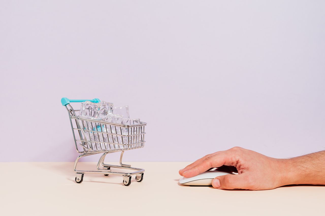 Menus Conceptual image of a hand on a mouse next to a miniature shopping cart filled with ice cubes, symbolizing online shopping.