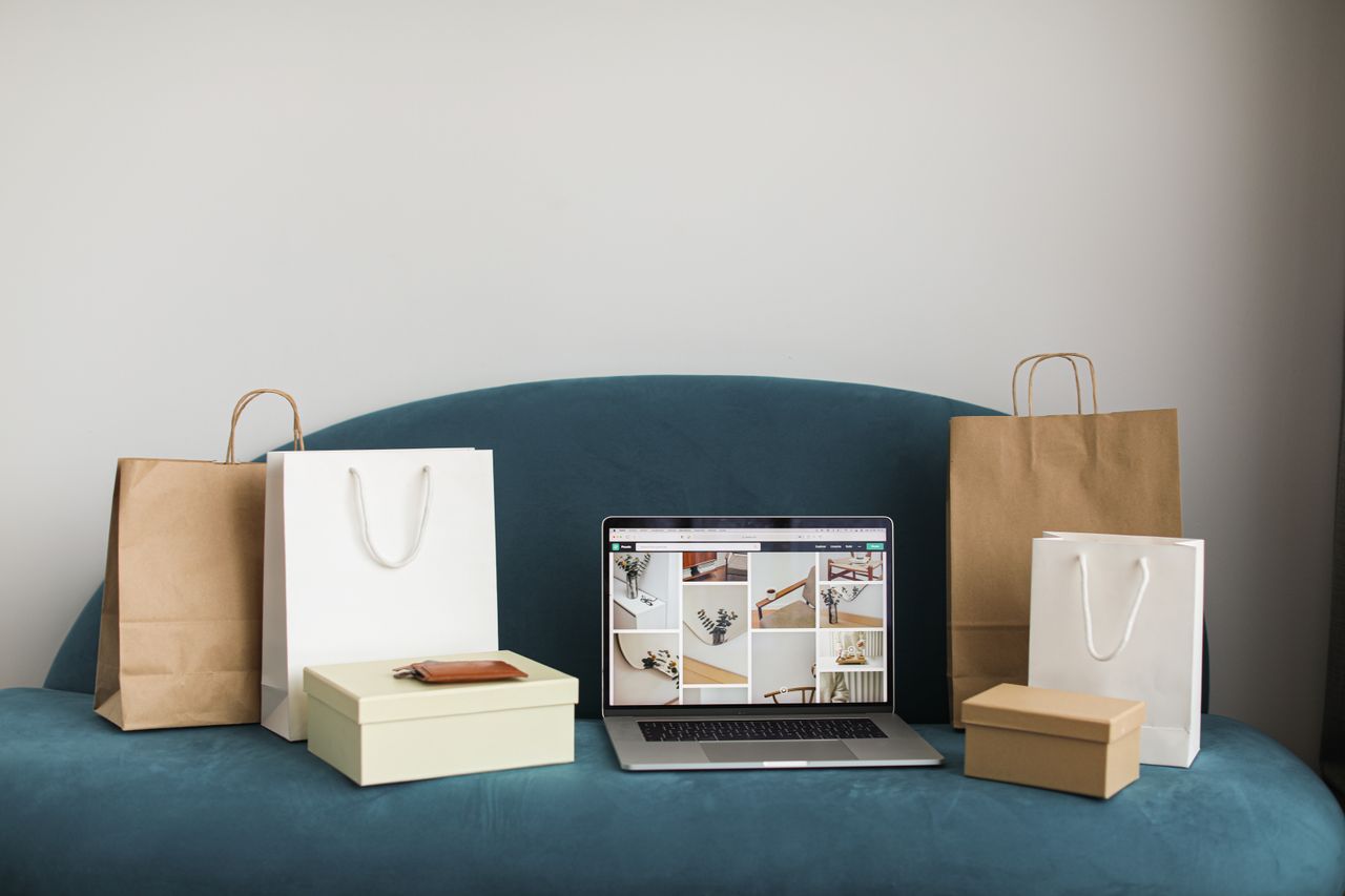 About A laptop surrounded by shopping bags and boxes on a blue sofa, ideal for online shopping themes.