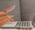 Close-up of a person using a credit card for online shopping on a laptop.