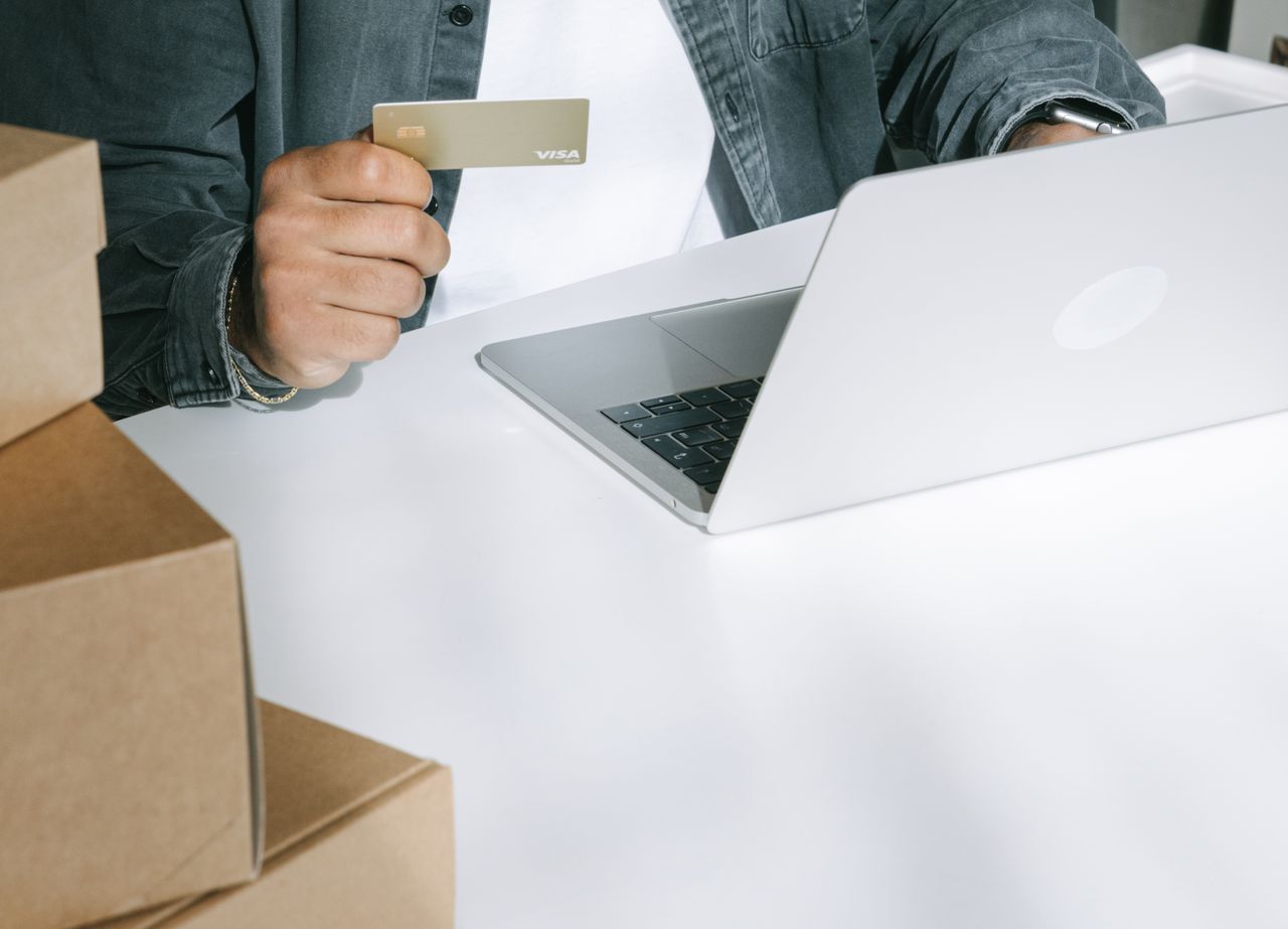Menus Person using a credit card for online shopping on a laptop surrounded by shipping boxes.